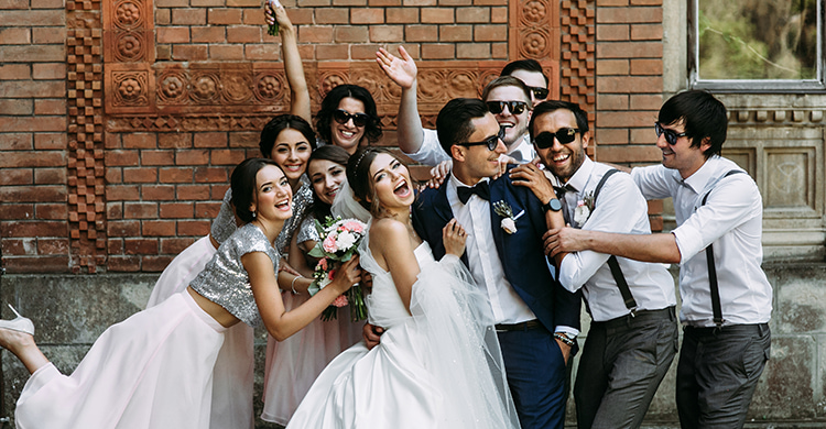 A bride and groom smile with wedding party in Eugene